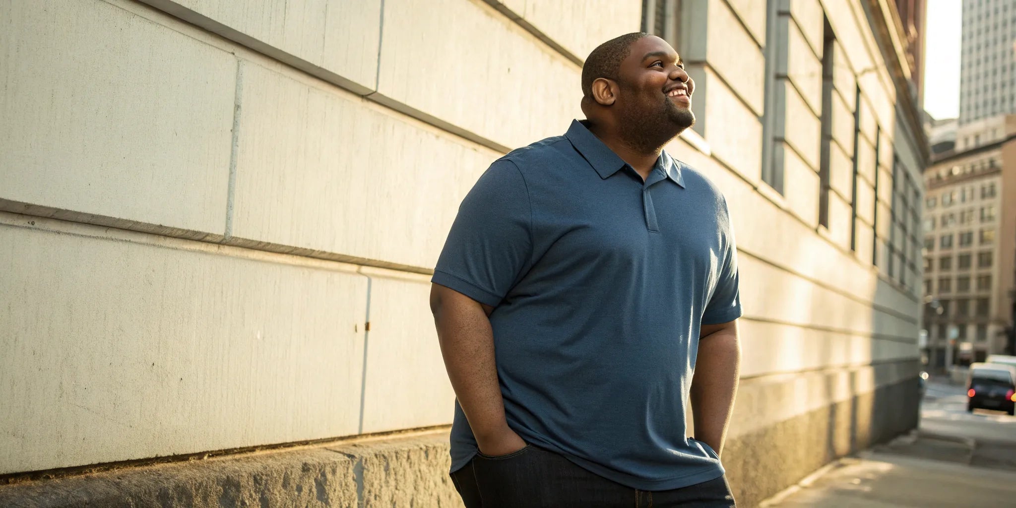 A big and tall man confidently wearing a blue polo shirt with spandex.